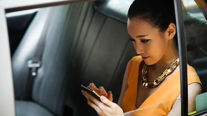 Young businesswoman in Hong Kong taxi, using smartphone.