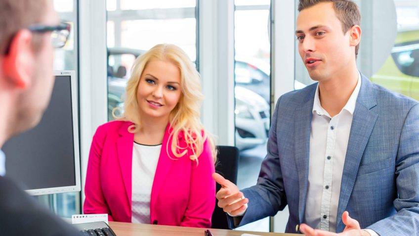 couple negotiating the price of a car with a salesperson