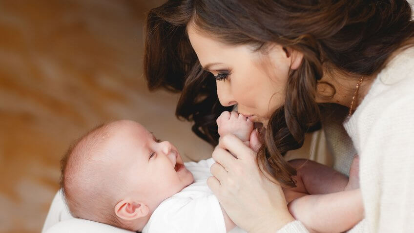 Expand paid family leave and affordable child care policies. mom kissing infant hands