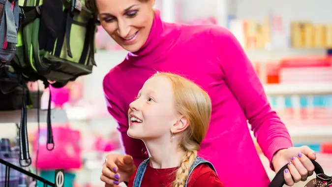 A woman and her daughter smiling and shopping for back-to-school items.