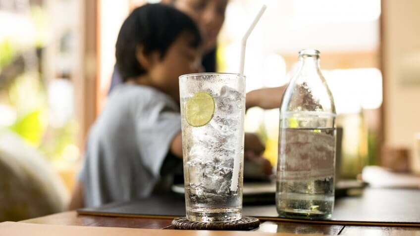 Healthy nutrition of drinking water with lemon and people in blur background.