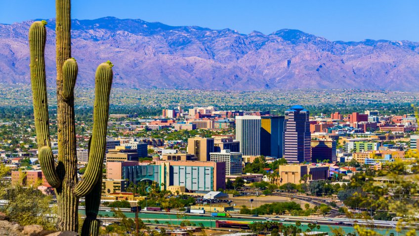 Tucson Arizona skyline cityscape framed by saguaro cactus and mountains.