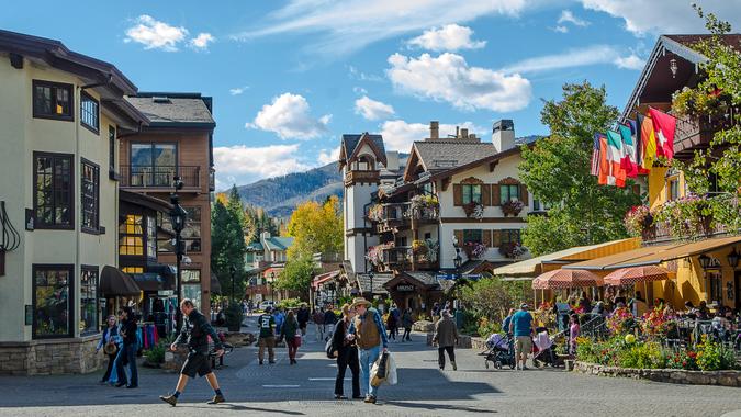 Vail, Colorado, USA - October 11, 2015: Residents and tourist walk and ride bikes on a beautiful Fall afternoon through the luxurious resorts, condominiums, chalets, shops and restaurants in the famous ski village of Vail, Colorado.