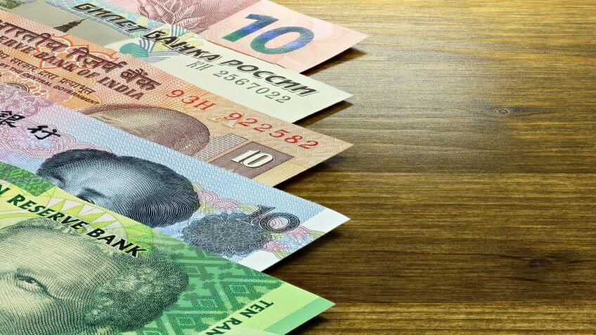 Biggest Money Scams of All Time, bank notes of the BRICS states on wooden background