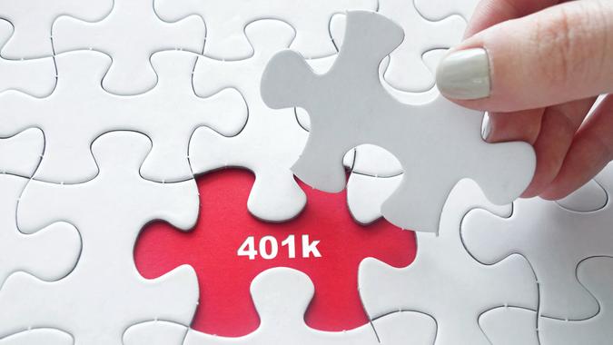 Close up of girl's hand placing the last jigsaw puzzle piece with word 401k.