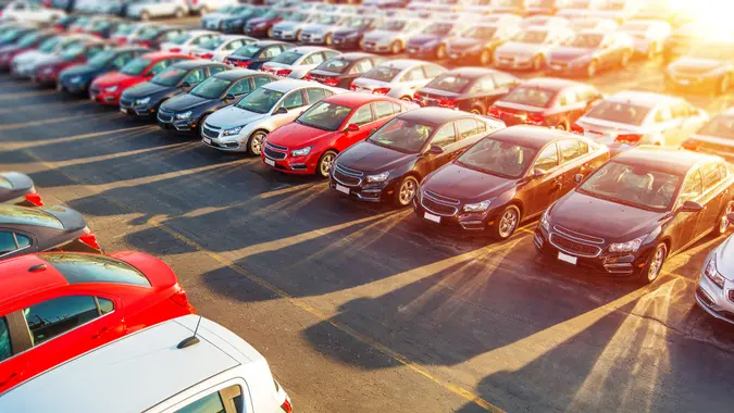 A car dealership showcasing numerous parked cars with the sun setting on them.