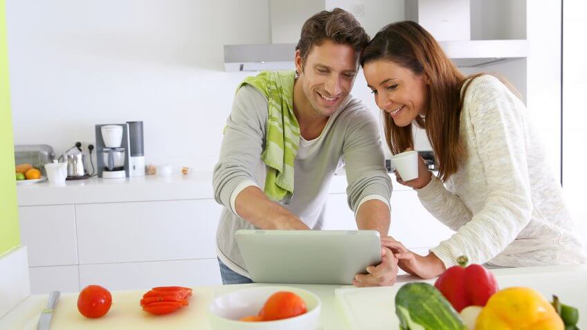 Couple in home kitchen looking for lunch recipe.