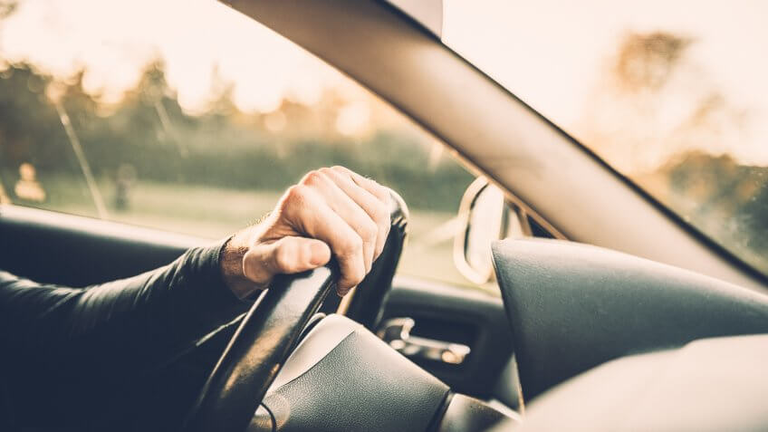 Man driving a car, close up on a steering wheel.