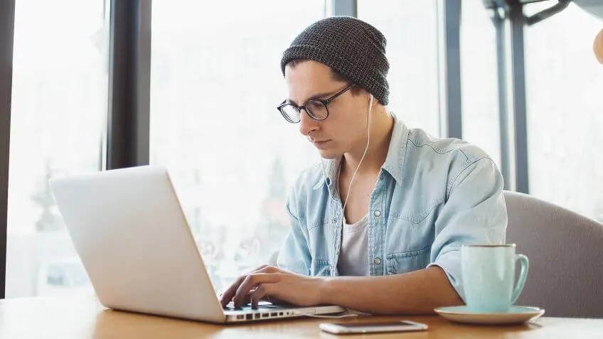 man with beanie and headphones using his laptop