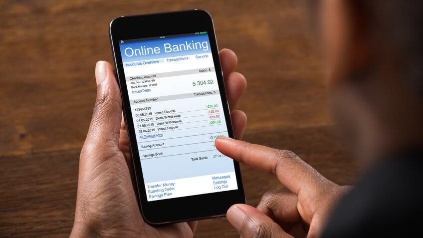Close-up Of Young Businesswoman Using Online Banking On Mobile Phone In Office.