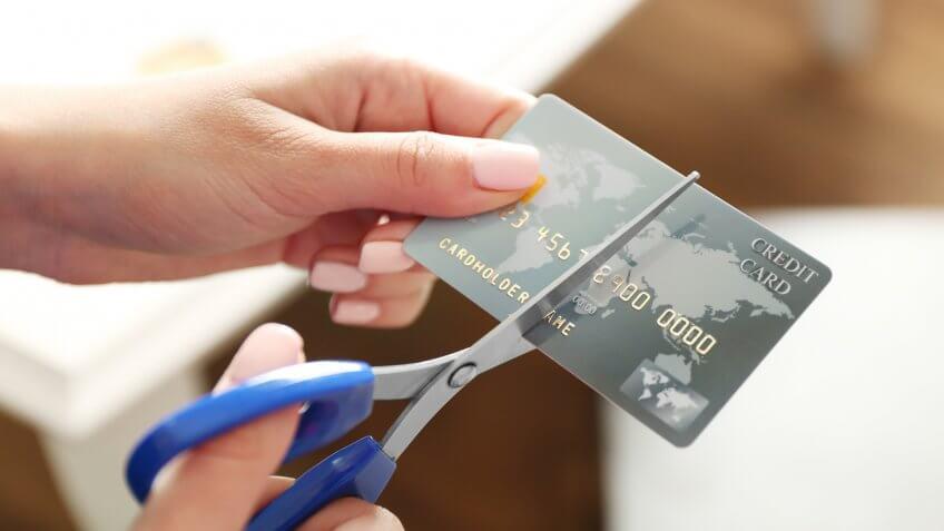 person cutting their credit card with scissors