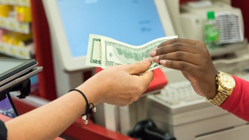 Woman giving cash when paying at a supermarket.