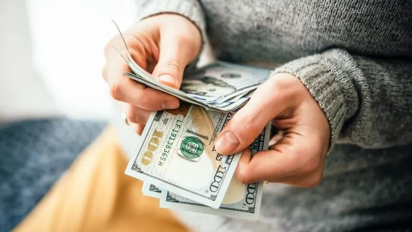 woman counting $100 bills cash money