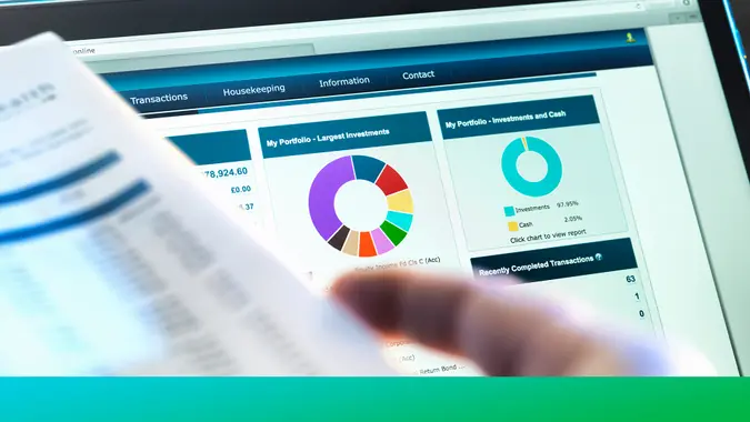 Investor checking performance of financial portfolio online whilst reviewing investment statement.
