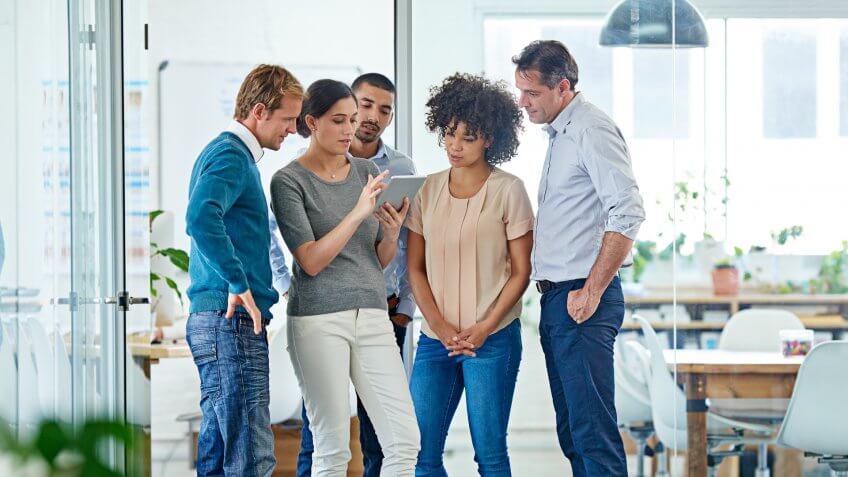 Shot of a group of office colleagues having a discussion over a digital tablet.