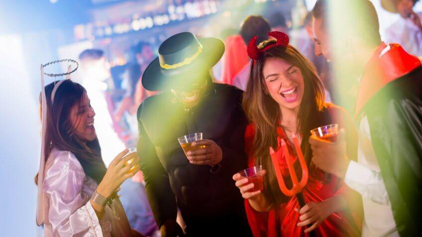 Group of people partying in Halloween and wearing different costumes at a nightclub.