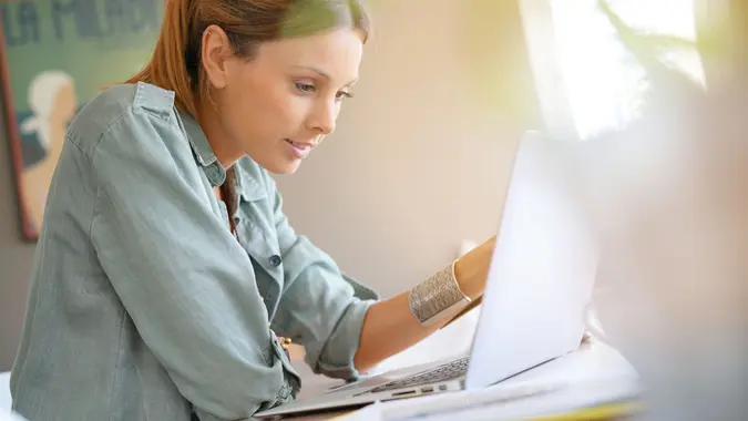 A young woman working on her laptop at home.