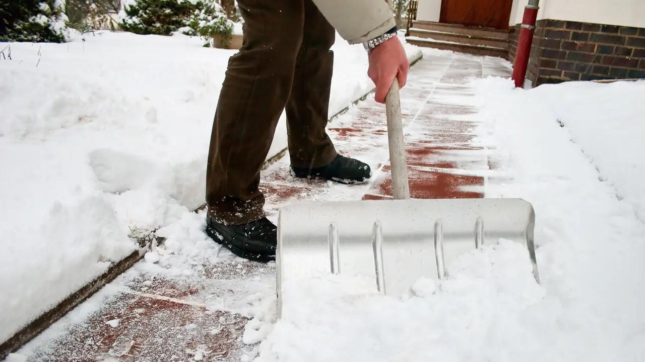 Man shoveling snow at a footpath.