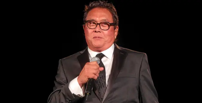 Robert Kiyosaki standing on a stage with a microphone.