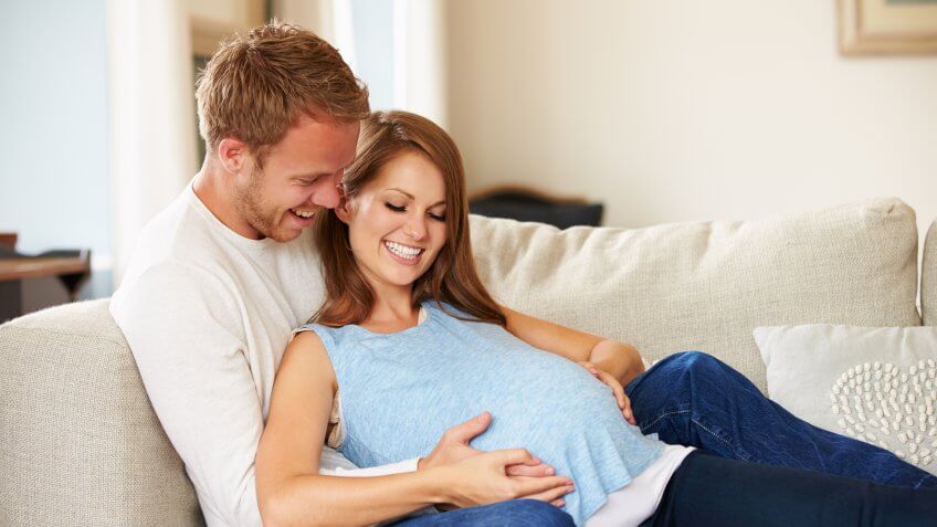 You have another baby on the way. husband laying down with pregnant wife