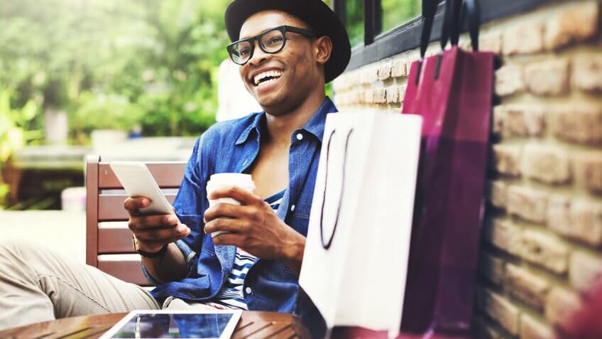 You rely on shopping to brighten your mood. man laughing with phone and coffee in hand