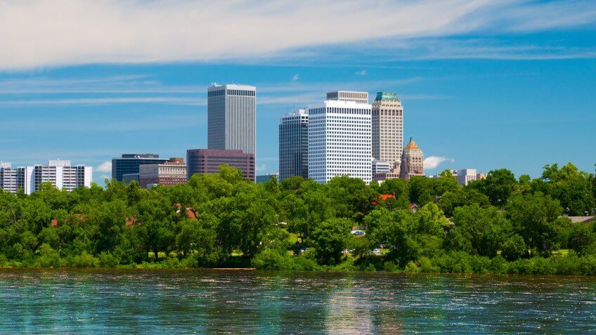 Tulsa downtown skyline with trees and the Arkansas river in the foreground.