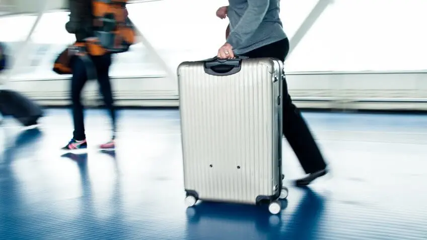 An unidentified person rolling a suitcase through an airport,