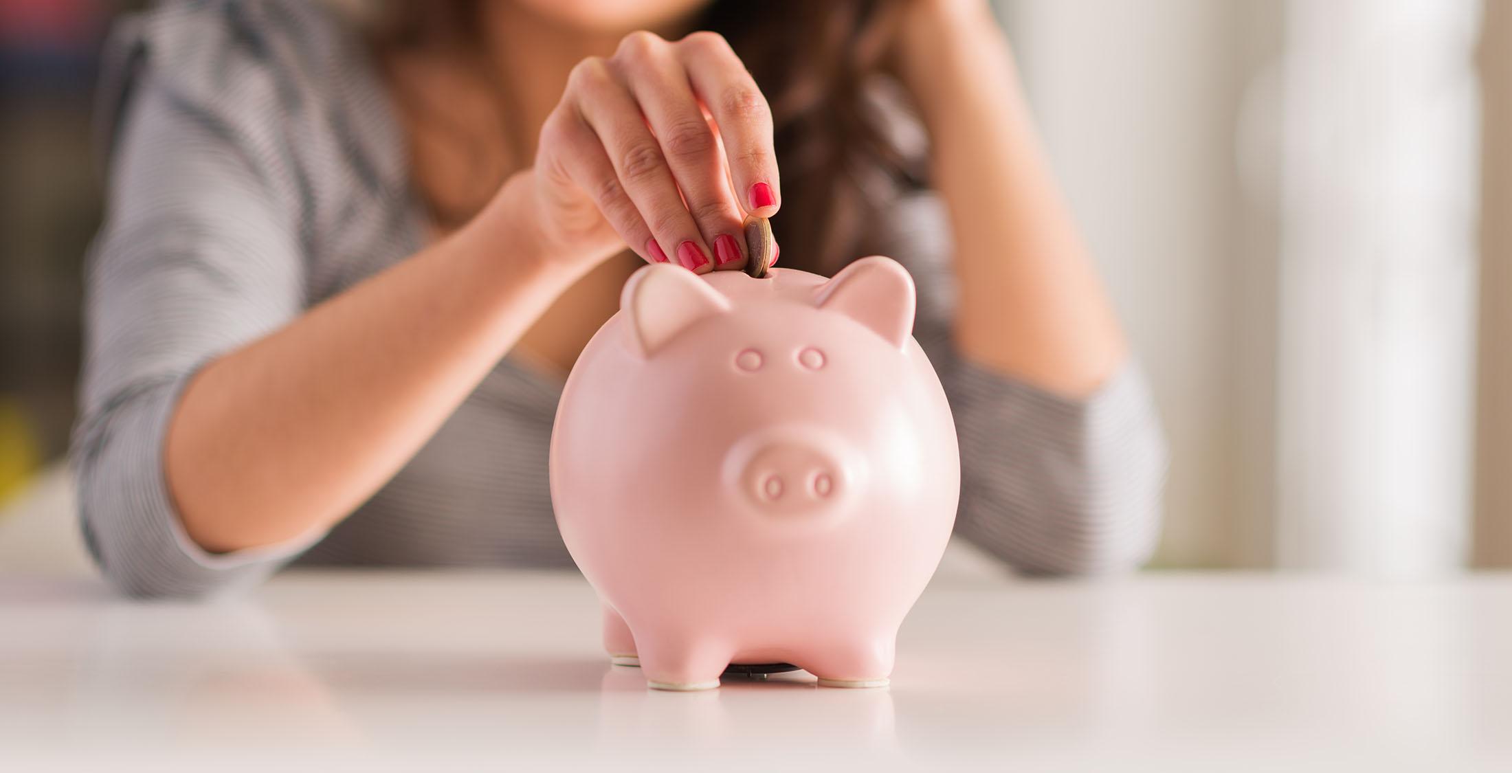 woman insert coin into piggy bank