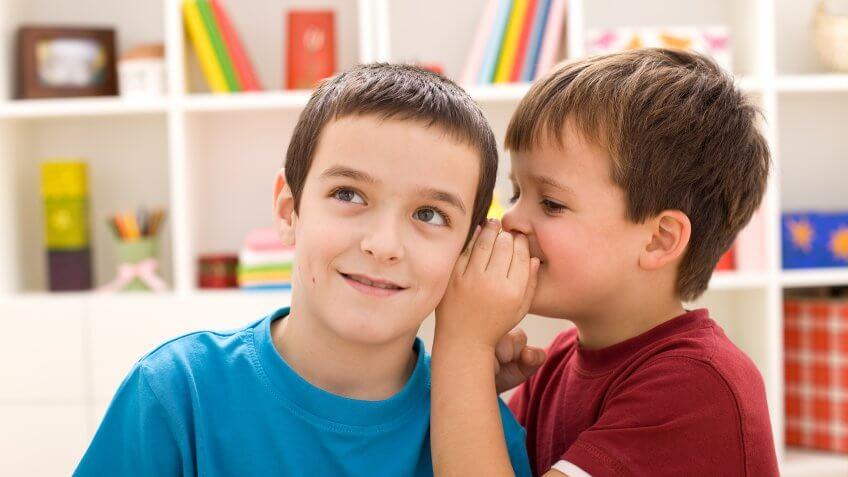 boy whispering into brother's ear