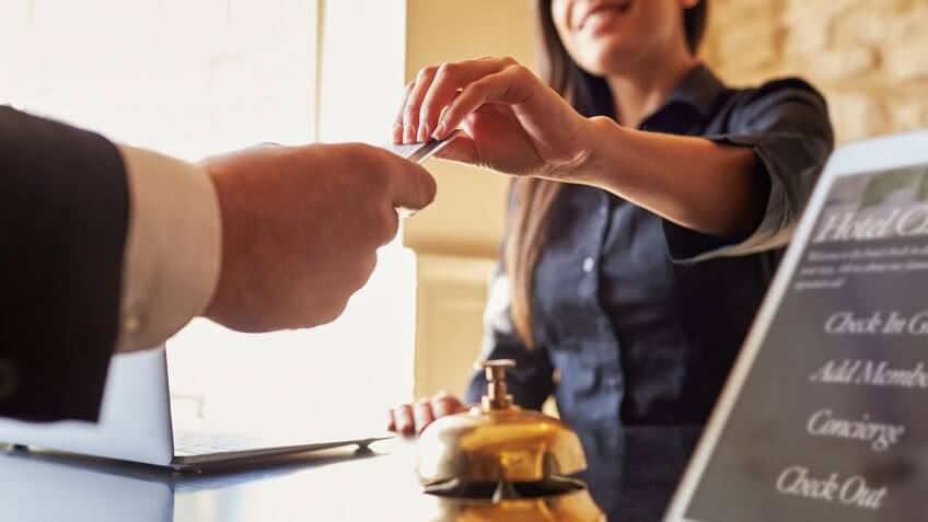 Hotels are less costly, too. concierge handing card to businessman