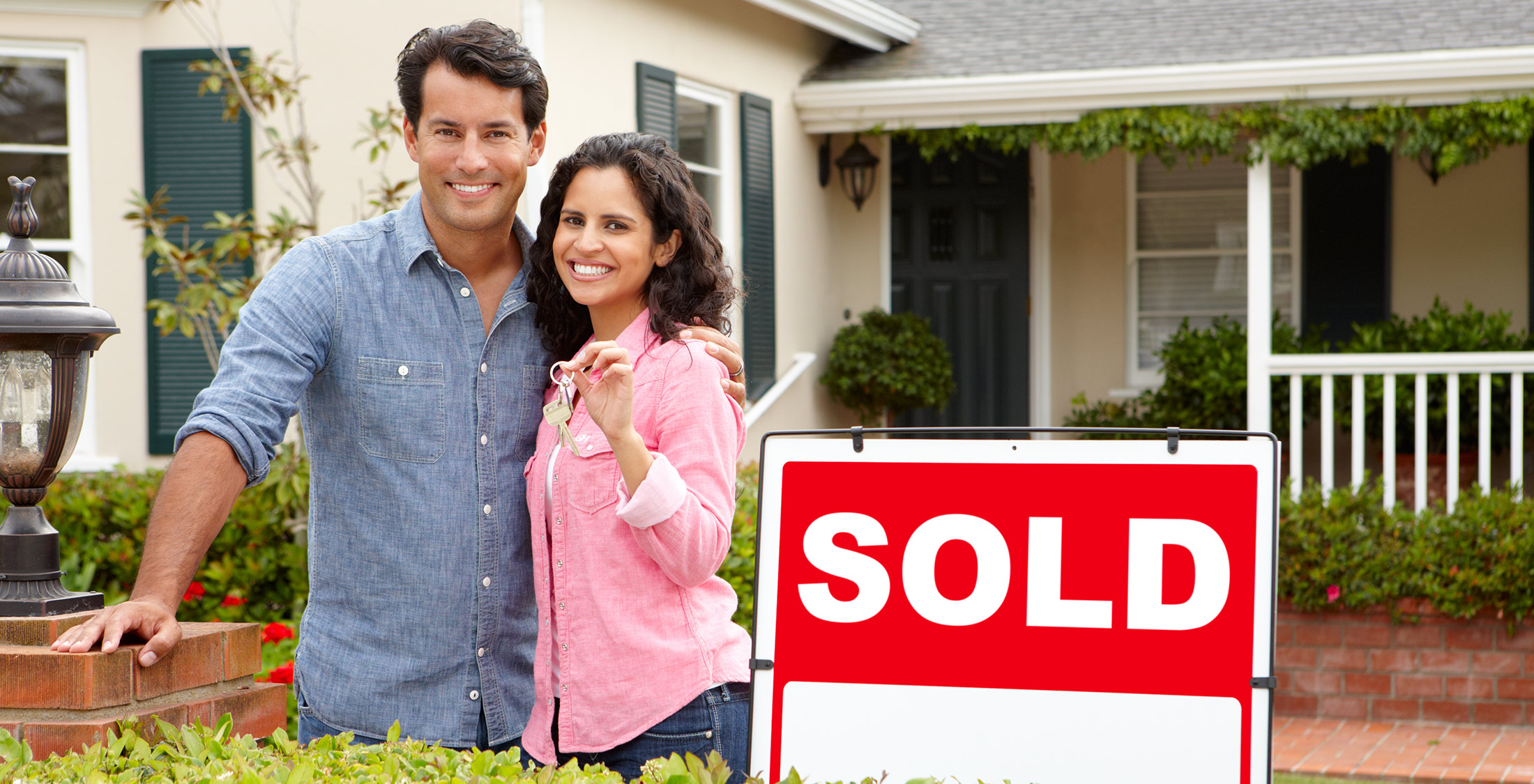Rent and mortgage is more affordable. couple standing in front of sold house