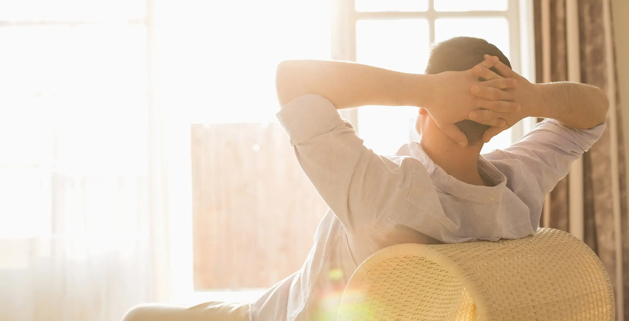man relaxing in chair with sunlight pouring in through window