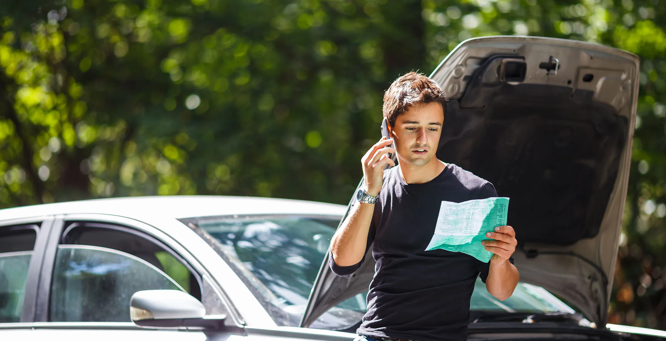 man on phone in front of car