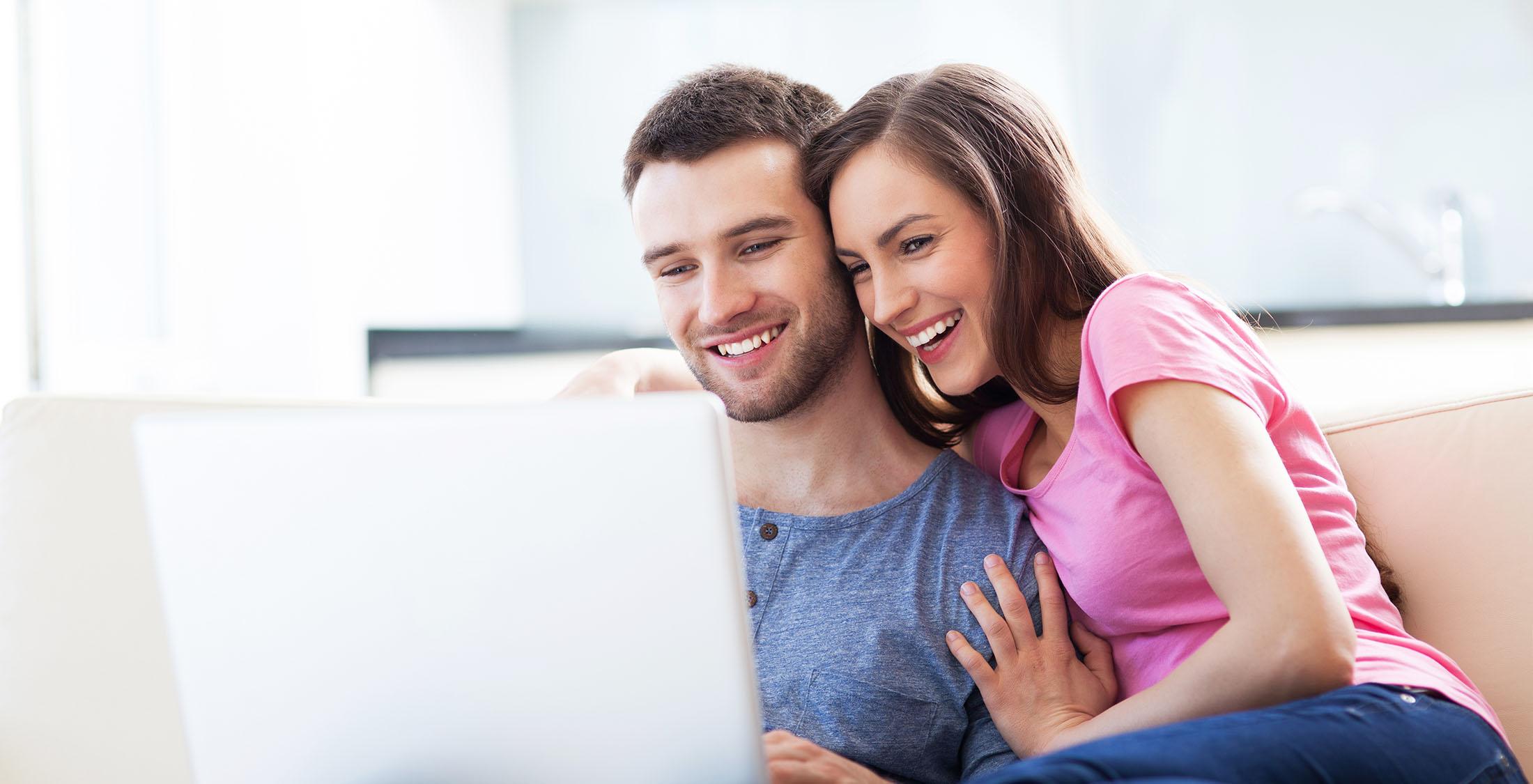 couple sitting on couch looking at computer