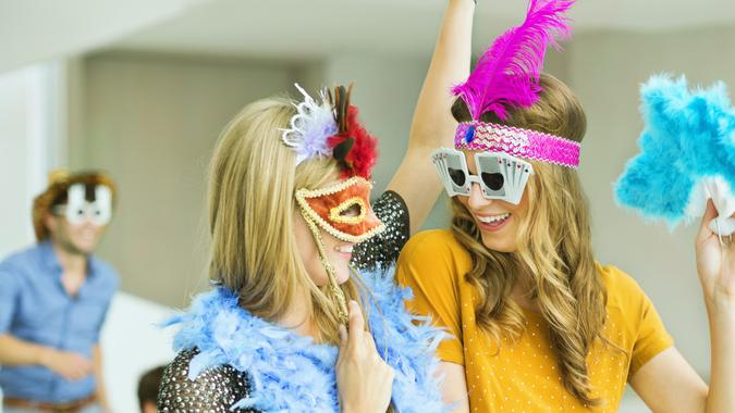 Women wearing decorative glasses and headpieces at party.