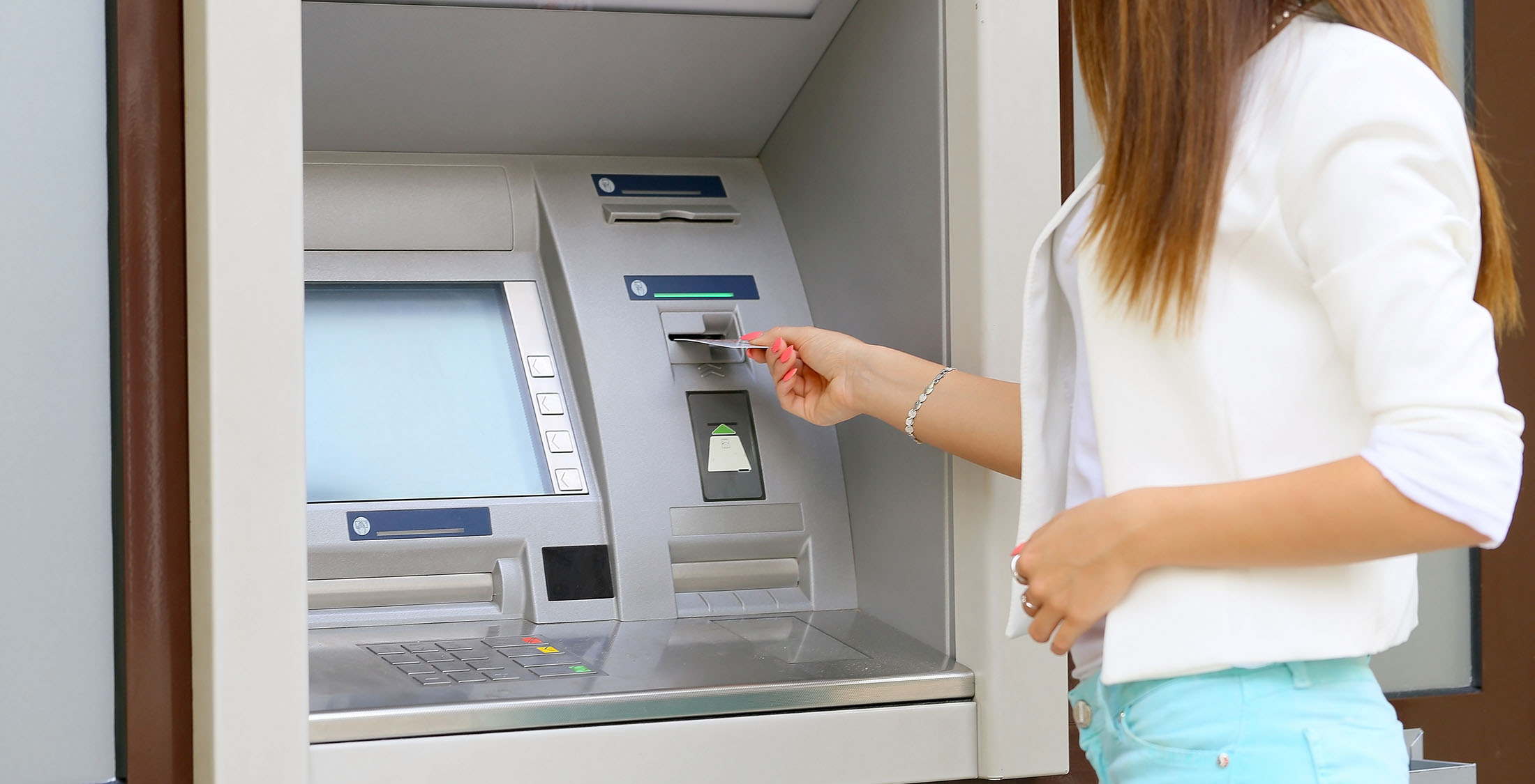 You withdraw from the ATM too much. woman putting card into atm