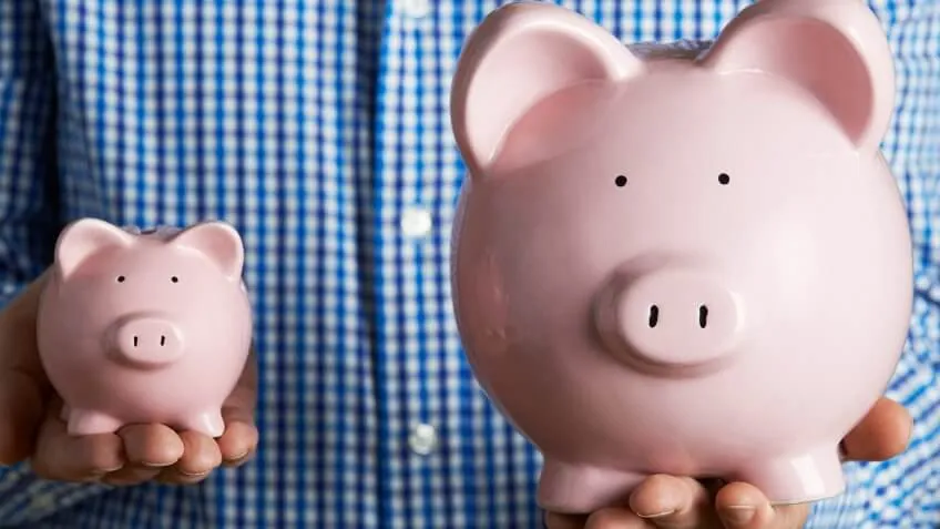 man holding a small and large piggy bank