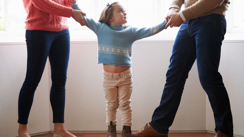 You are being a competitive parent. parents tugging daughter by arms