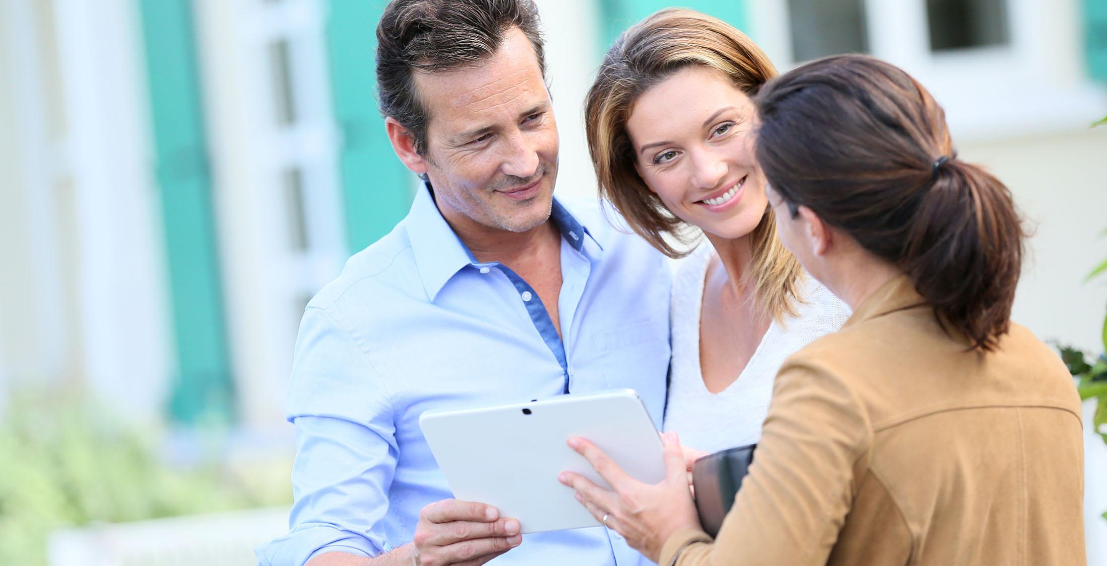 real estate agent showing couple something on tablet