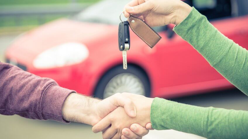 Sell your car as-is. woman handing over car keys to man
