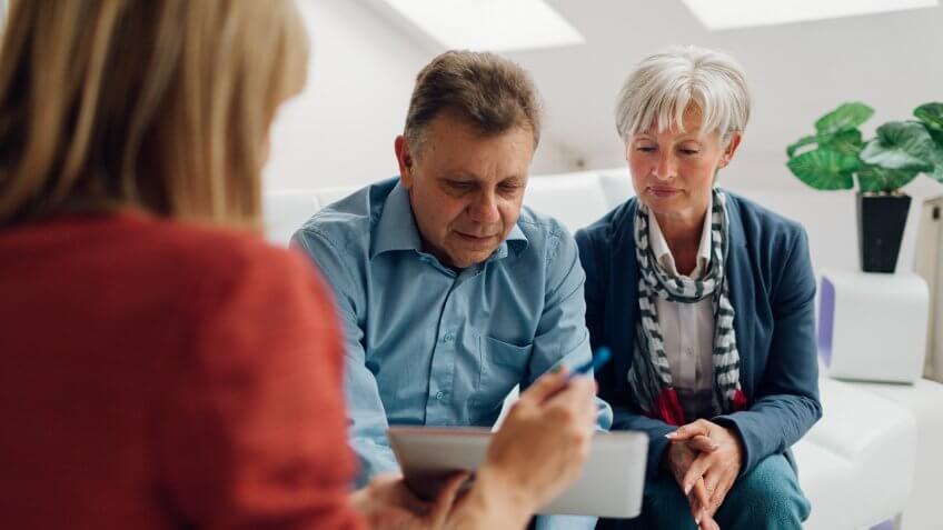 Mature Couple Meeting with Financial Advisor, selective focus to senior man and mature woman listening to financial advisor.