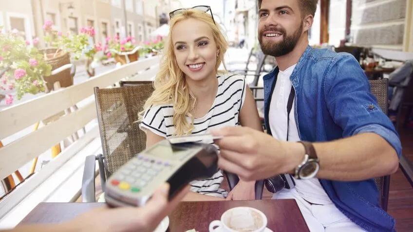 young couple paying for coffee with wireless credit card pay