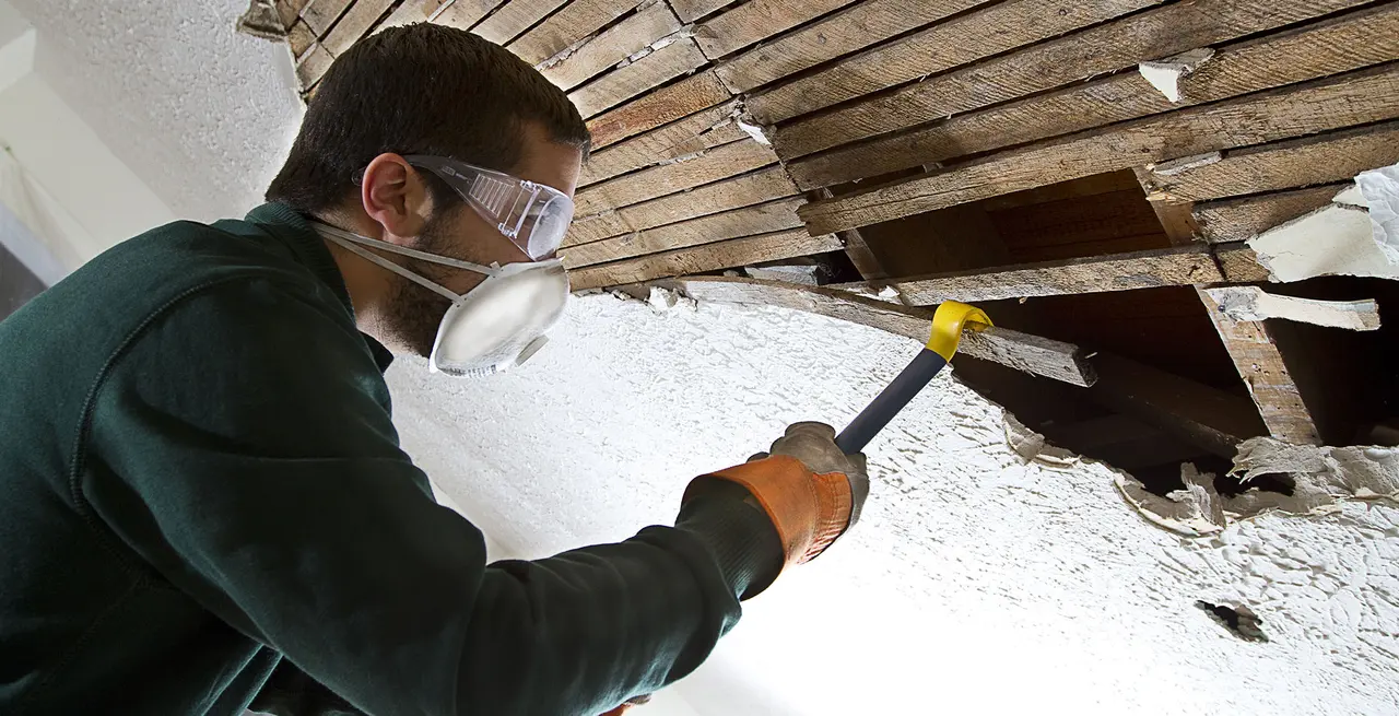man taking apart wall with crowbar