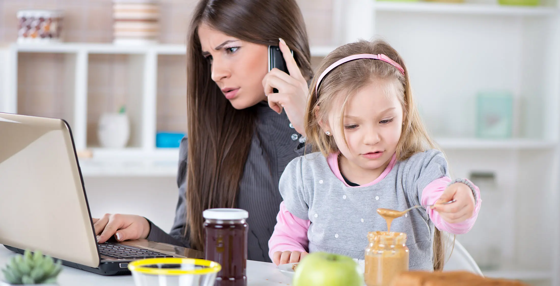 kid scooping peanut butter while mom is on phone
