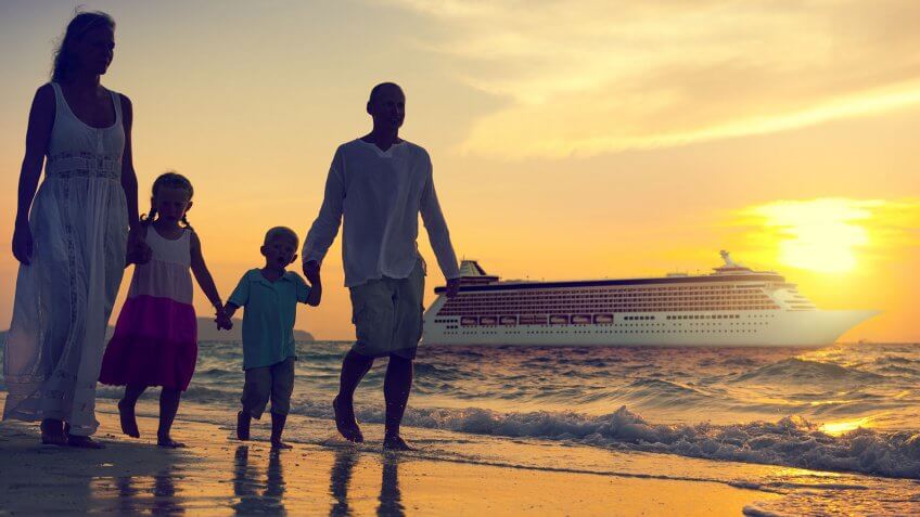 Cruises aren't that expensive. family walking hand-in-hand on beach at sunset