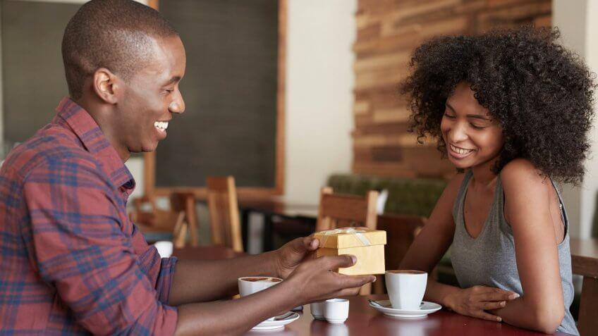 man giving a woman a gift at a coffee shop