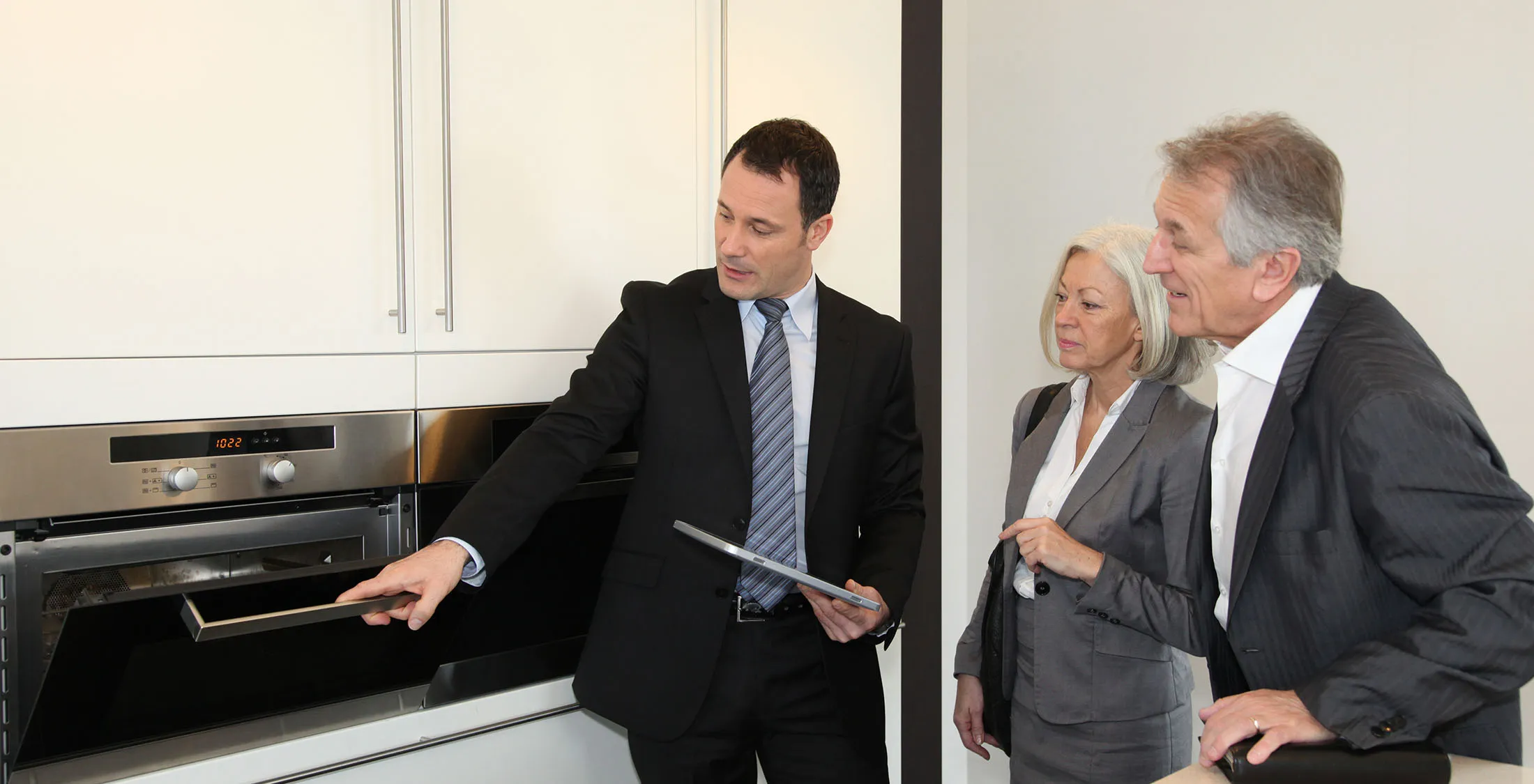 real estate agent showing elder couple an oven