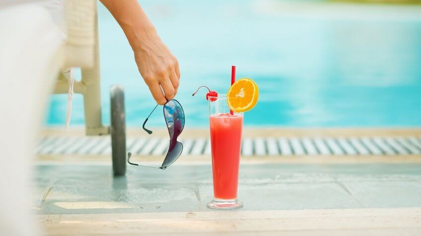 Less crowded flights and tourist spots could equal better, more relaxed service. alcoholic drink by person's side at the pool