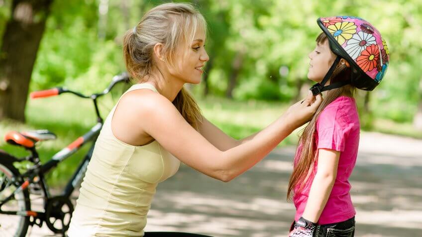 mom fastening helmet on daughter