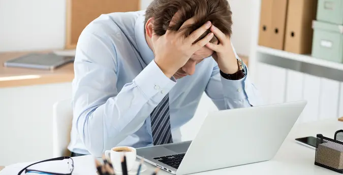 stressed man hunched over laptop